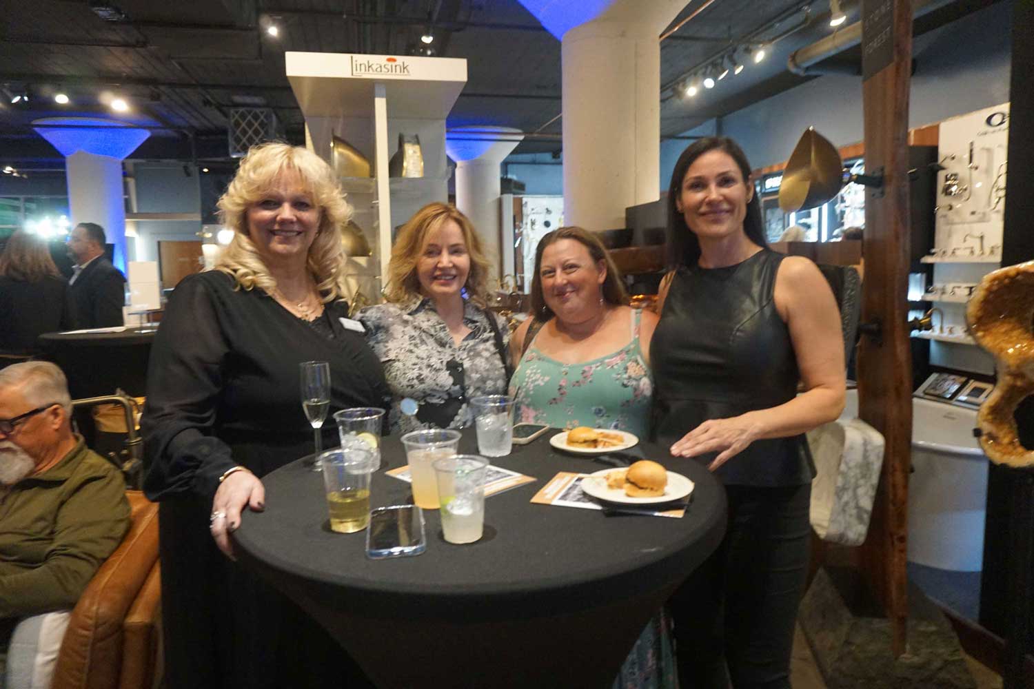 Four women standing around a cocktail table in the showroom.