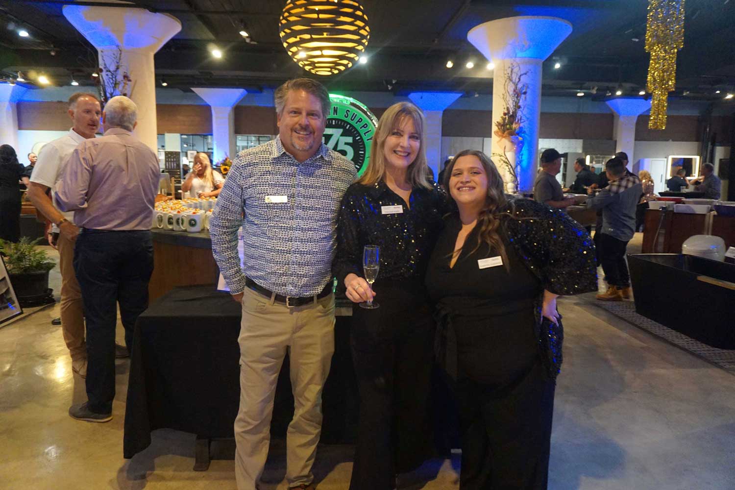 Three people smiling next to the anniversary ice sculpture.