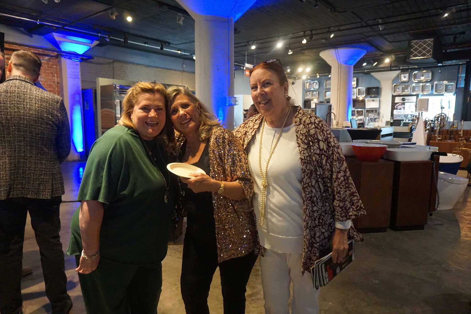 Three women standing together and smiling at the party.
