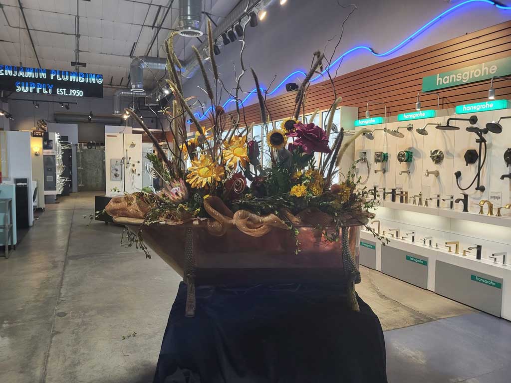 Floral arrangement in a white tub with a Monogram sponsor sign.