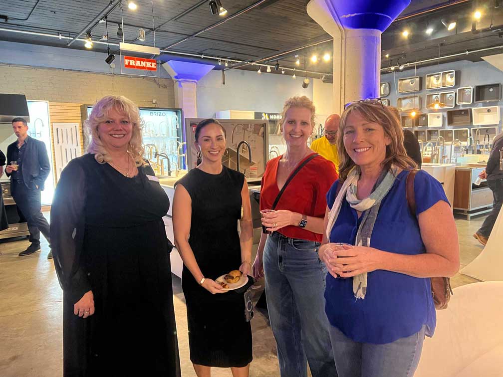 Four people standing together and smiling in the showroom