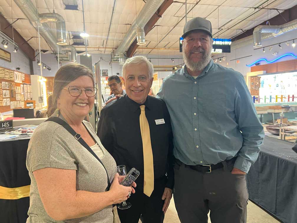 Three people posing together in the plumbing showroom during the event.