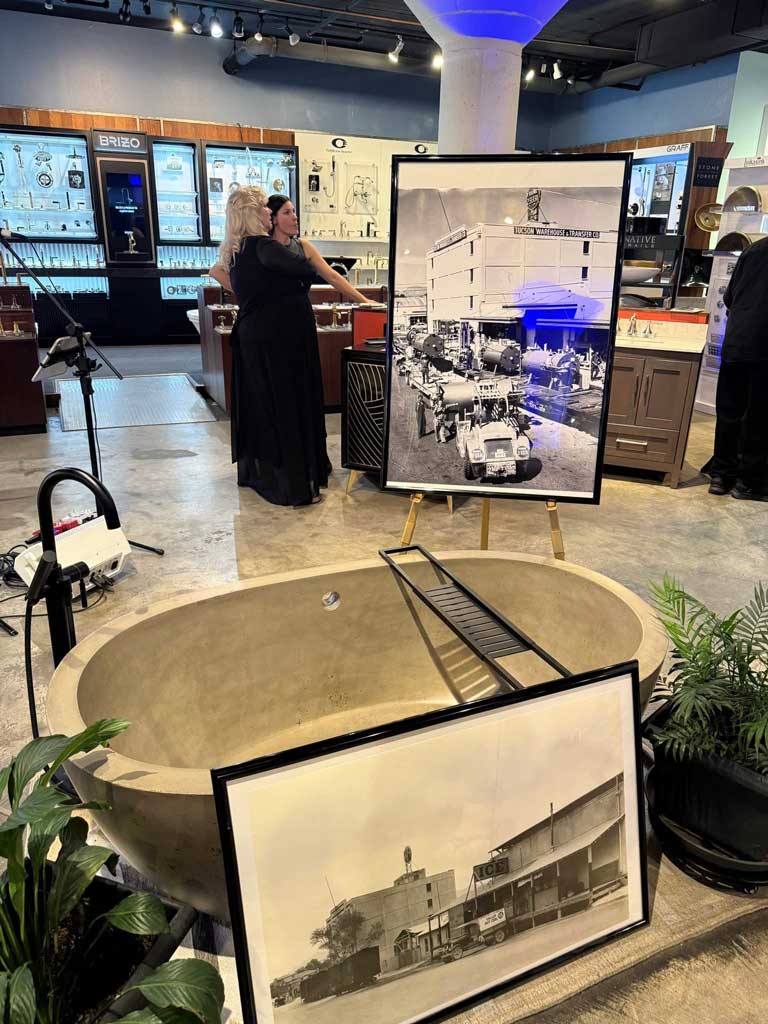 Historical black and white photos of Benjamin Supply displayed on easels in front of a concrete tub.