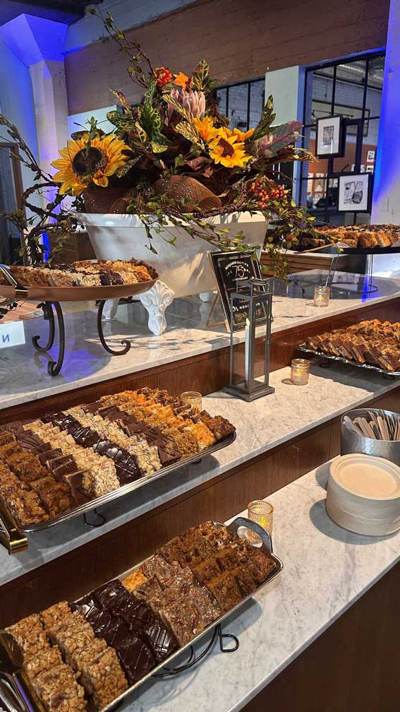 Dessert table featuring trays of bars and sweets.