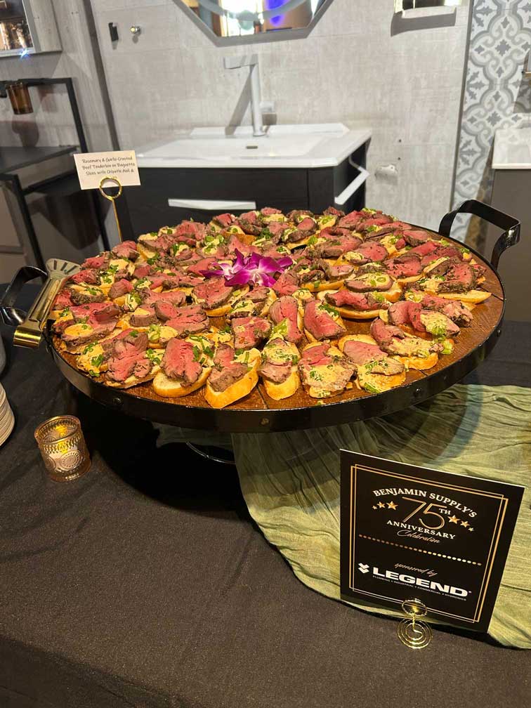 Round wooden platter with appetizers topped with orchids, sponsored by Legend.