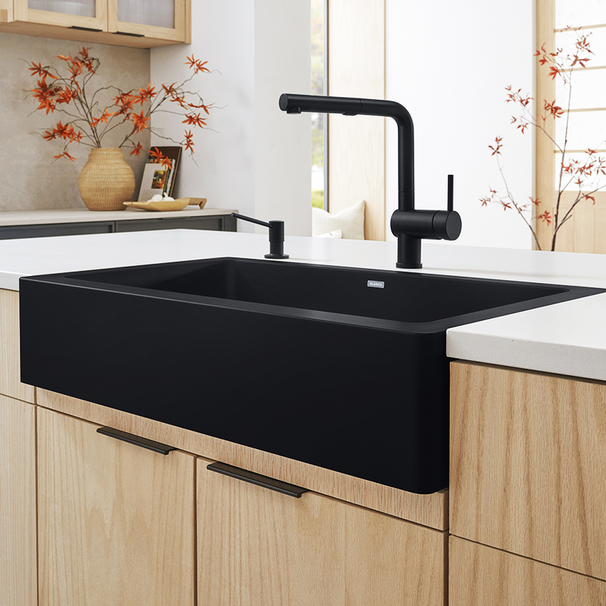 A black Silgranit sink with a faucet and accessories