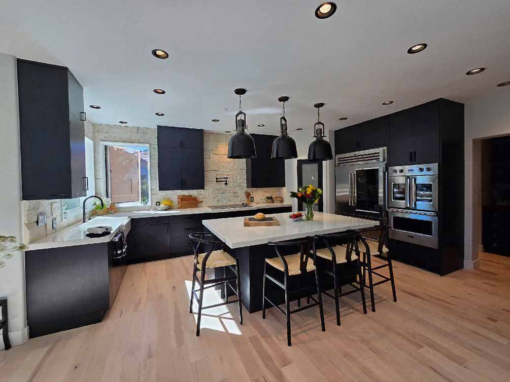 Modern kitchen with black cabinets, white countertops, and a large center island with pendant lighting