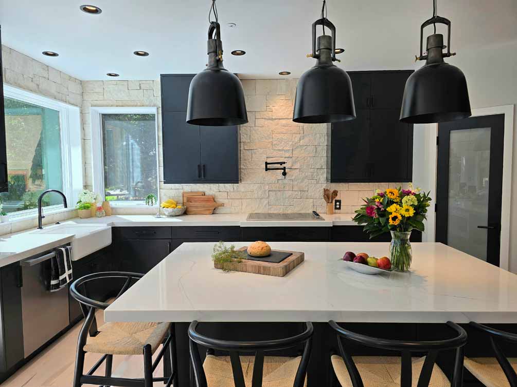 Close-up view of a modern kitchen island with a loaf of bread, fresh fruit, and a vase of sunflowers