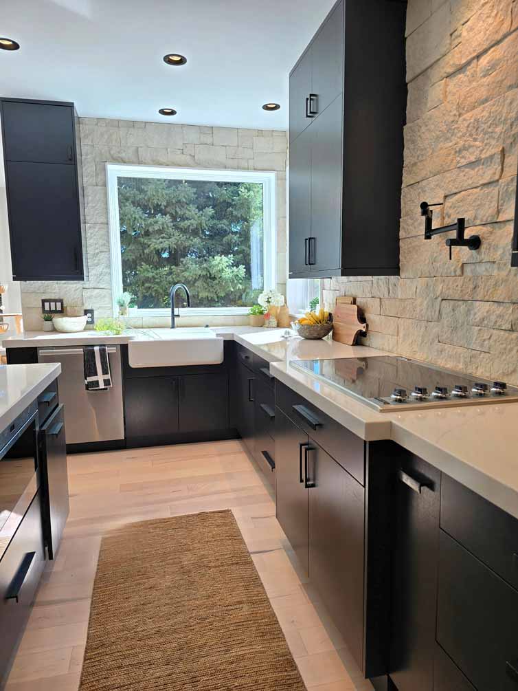 L-shaped kitchen corner with black cabinets, large windows, and a farmhouse sink beneath a scenic view
