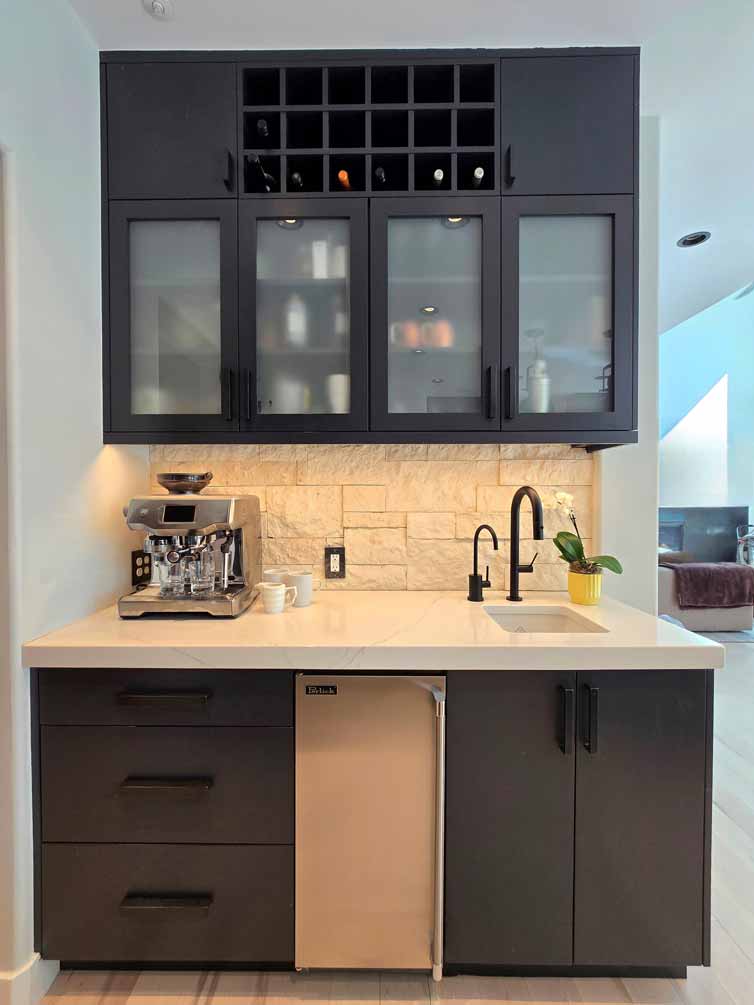 Compact beverage station with black cabinetry, mini fridge, espresso machine, and upper wine storage