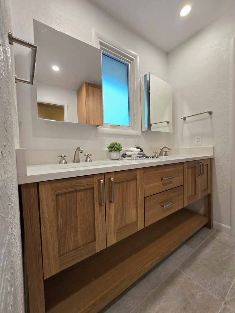 Warm wood bathroom vanity with dual sinks, mirrored cabinets, and white quartz countertop