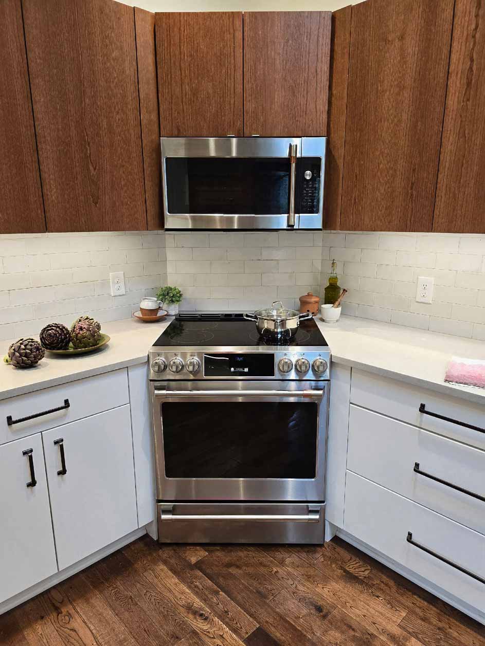 Close-up of stainless steel range and microwave surrounded by walnut cabinets and white backsplash