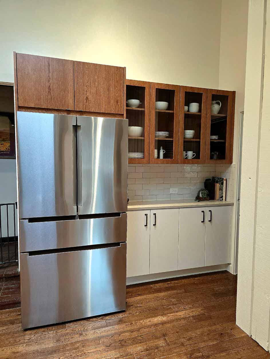 Kitchen corner with stainless steel French door refrigerator, glass-front cabinets, and neutral-toned counters