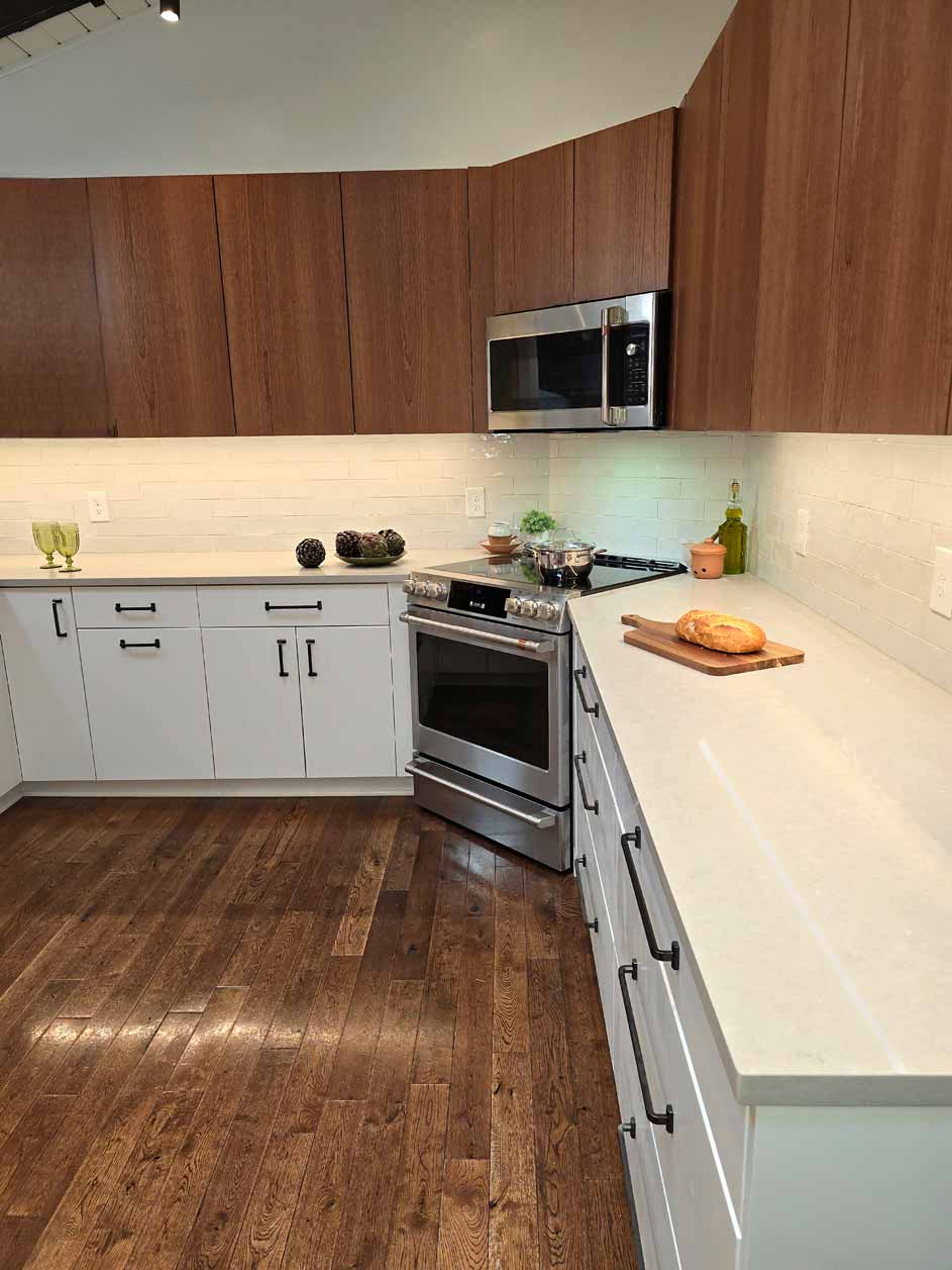 Wide-angle view of a midcentury kitchen featuring a stainless steel oven, white drawers, and wooden upper cabinets