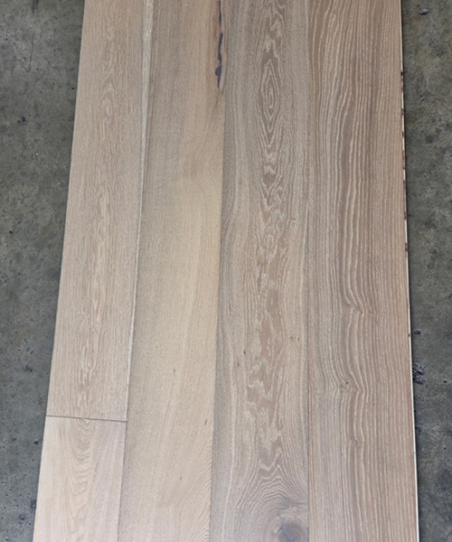 A close-up view of a white-finished wood floor, showcasing its smooth texture and light color.