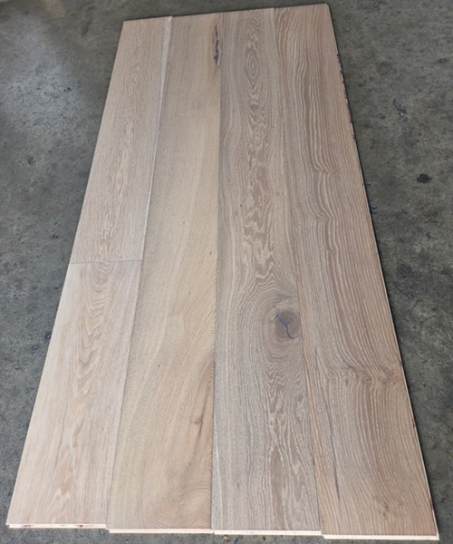 A close-up view of a white-finished wood floor, showcasing its smooth texture and light color.