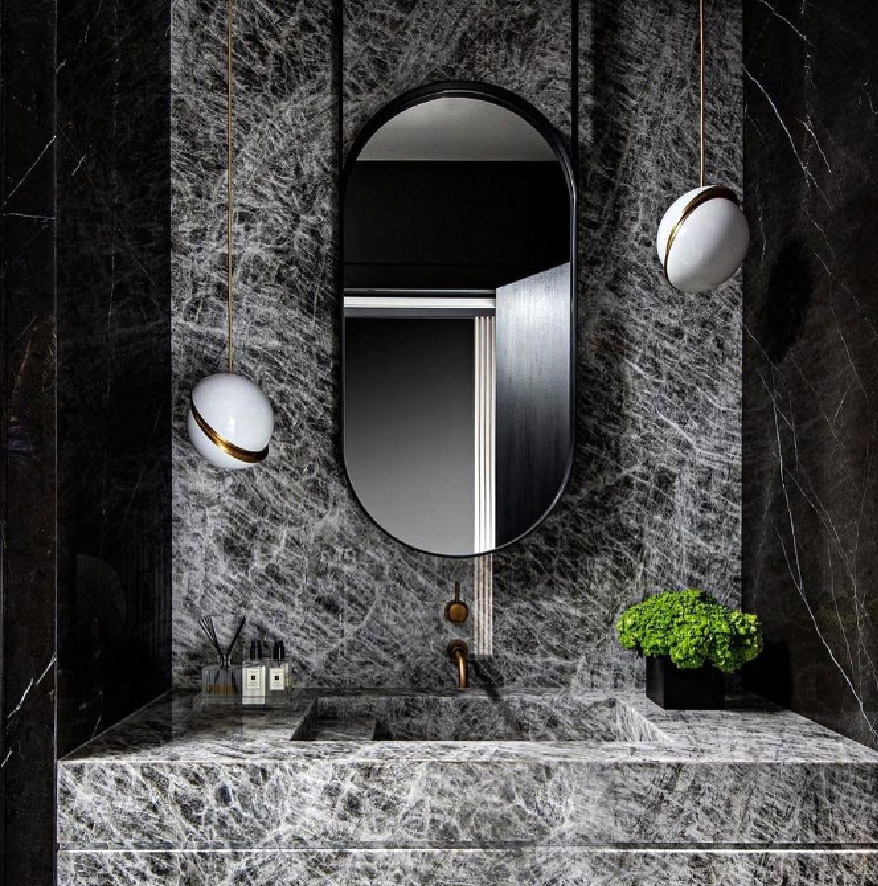 A dark bathroom with a vanity and a mirror