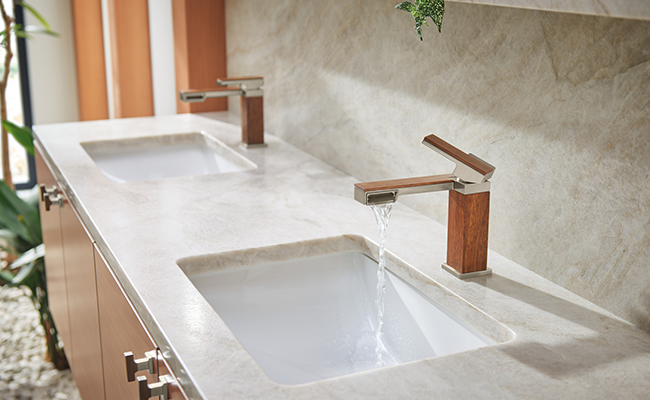 Two bathroom faucets in a bathroom with a mixed wood and metal finish