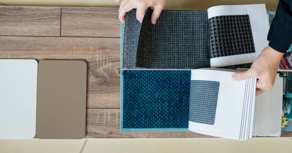 An Interior designer is choosing paints and textile materials for a home renovation. They're laying out samples on a board.