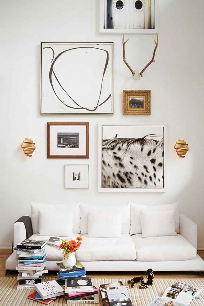 White modern room scattered with books with sconce lighting.