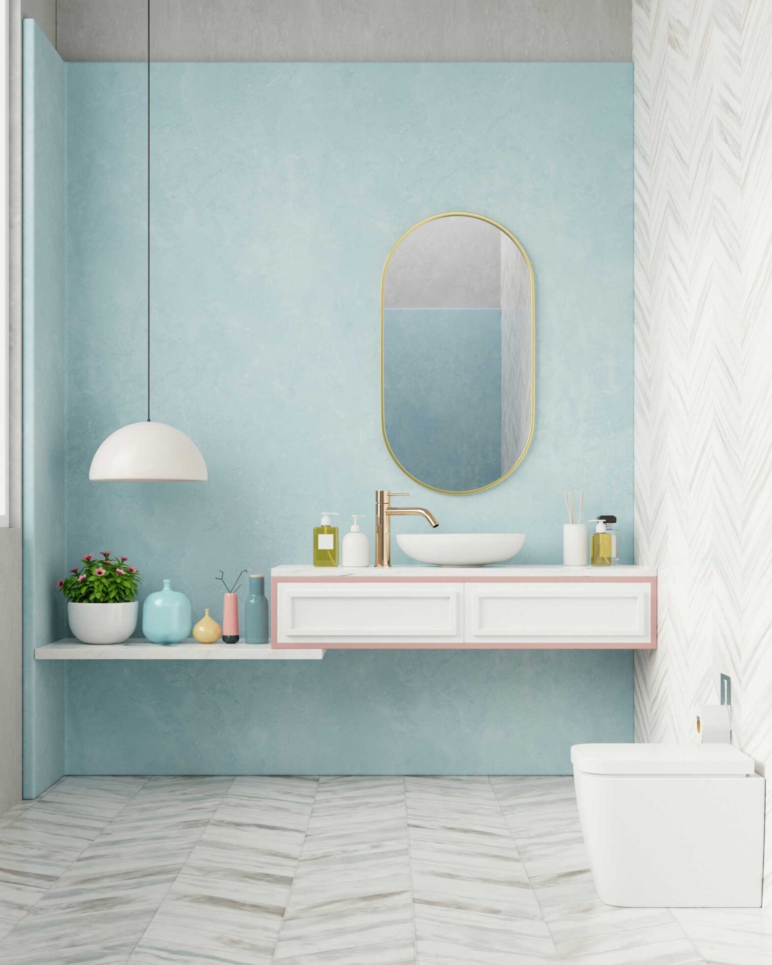 A stylish, modern bathroom with a light blue textured wall and a white floating vanity holding a vessel sink and gold faucet. An oval, gold-framed mirror hangs above. The floor and an accent wall feature light-colored, marble-look tiles in a chevron pattern.
