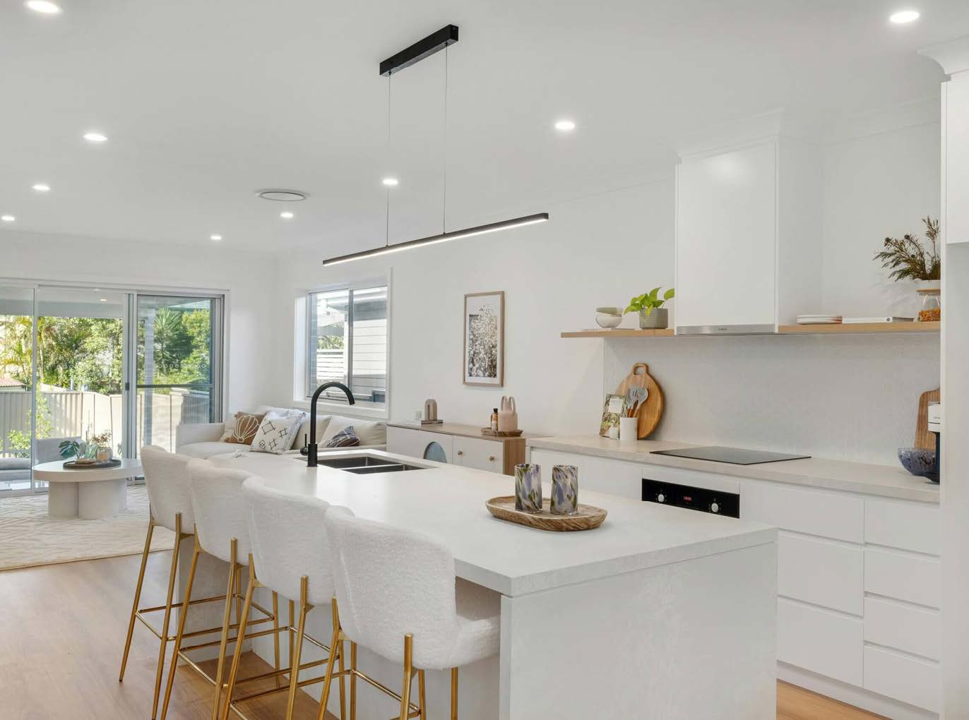 A bright modern bathroom with white and light wood cabinetry, seen through an arched doorway.