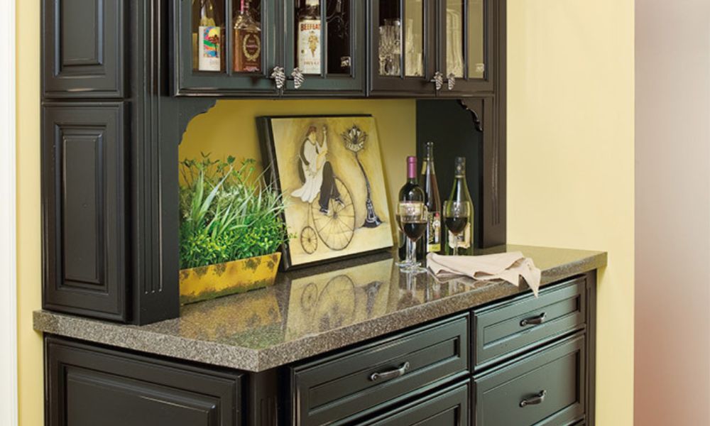 A close-up of a classic black wooden hutch or home bar, featuring a dark granite countertop, glass-front upper cabinets, and decorative molding.