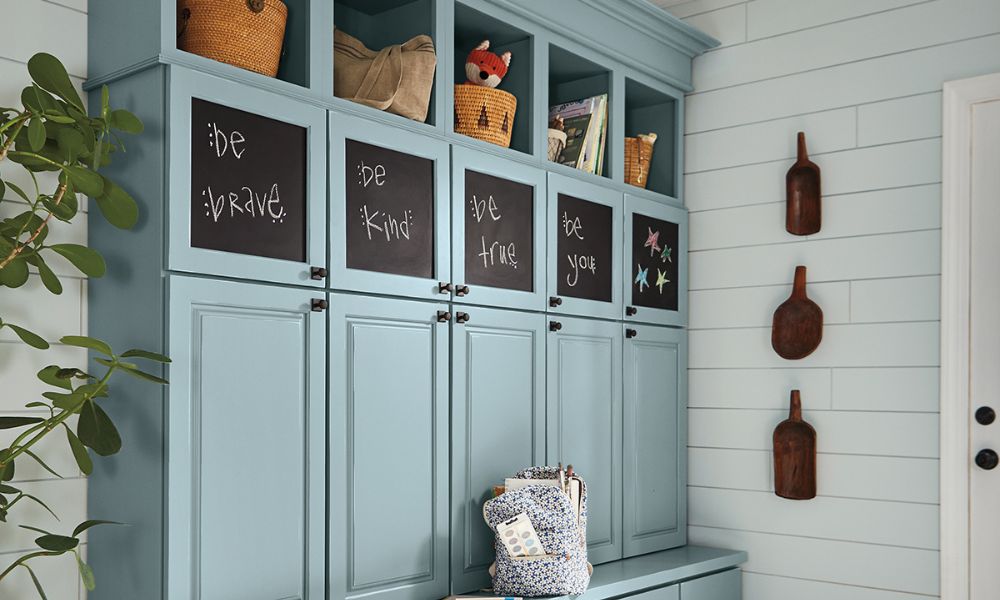 Mudroom with blue cabinets featuring chalkboard panel doors against a shiplap wall.