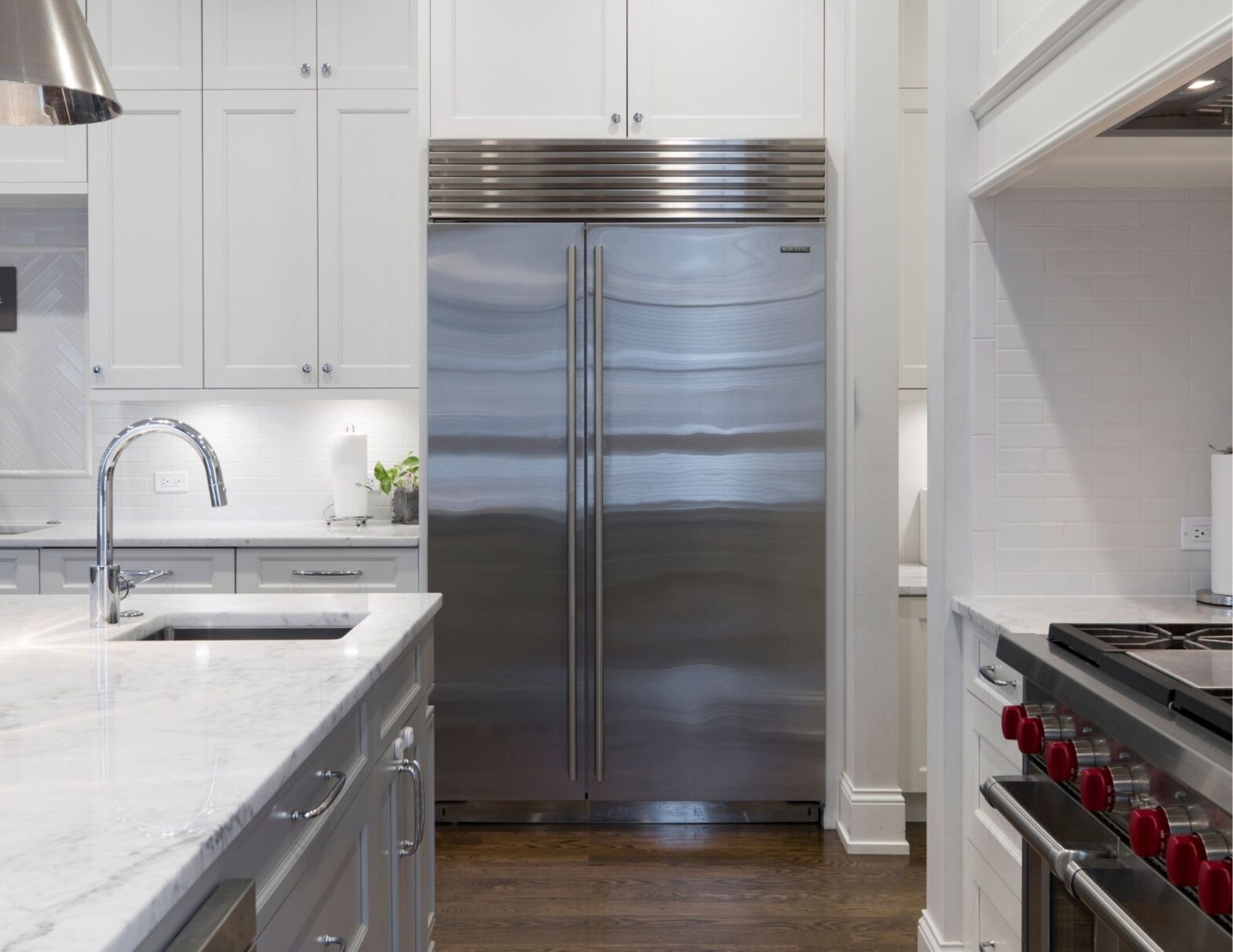 A modern kitchen featuring a stainless steel refrigerator and a sleek marble countertop.
