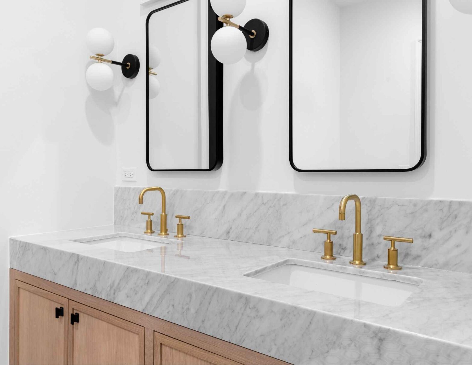 Modern bathroom with double vanity, gold faucets, and large rectangular mirrors