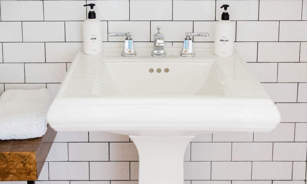 White porcelain pedestal sink in a bathroom with white subway tile