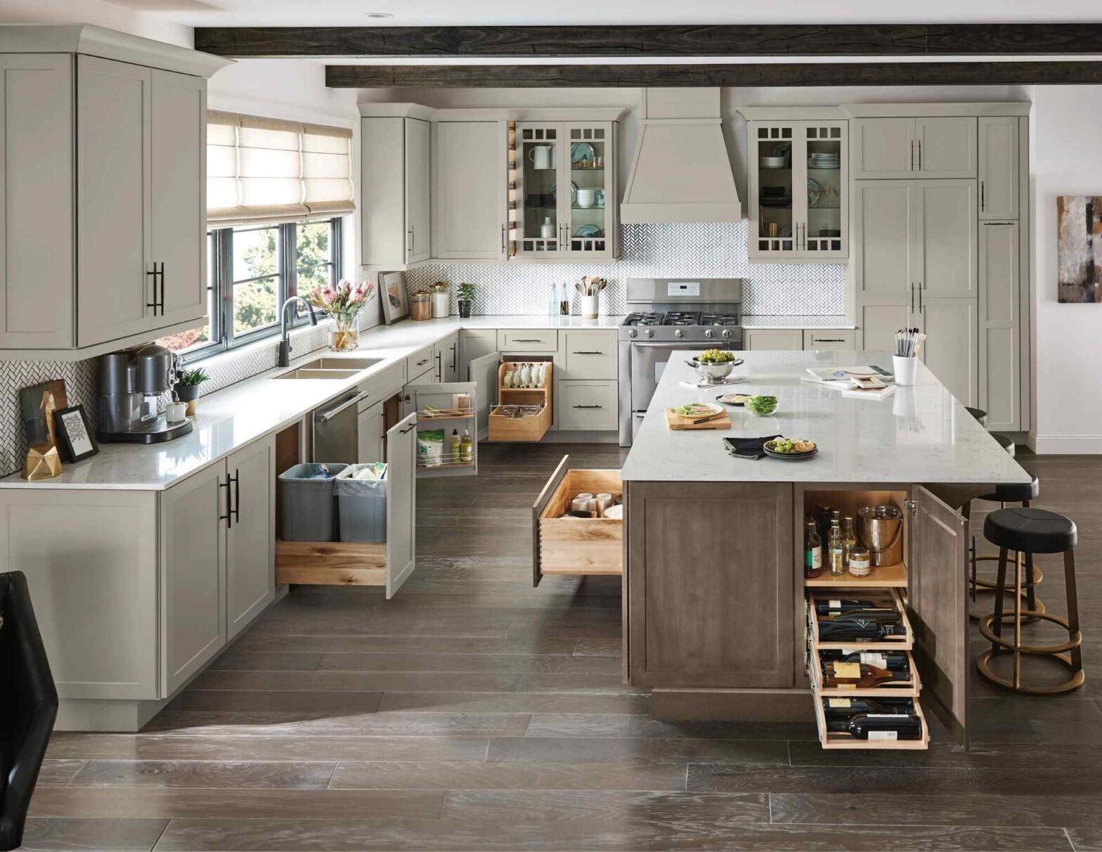 Spacious kitchen featuring Schrock Cabinetry with a large central island, open drawers showing storage solutions, and grey shaker-style cabinets.