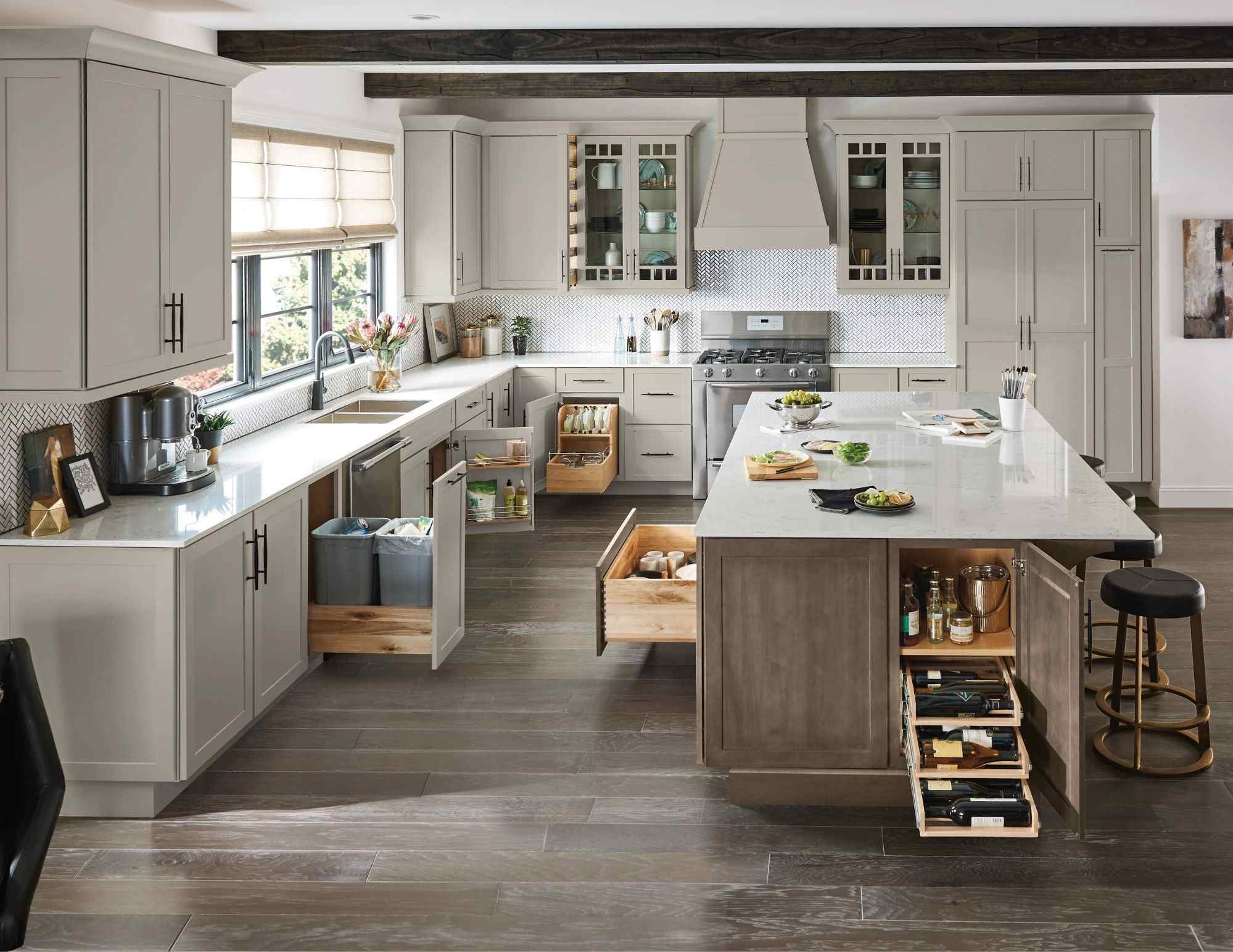 Spacious kitchen featuring Schrock Cabinetry with a large central island, open drawers showing storage solutions, and grey shaker-style cabinets