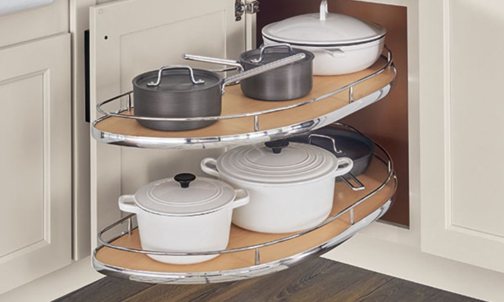 Open curved corner cabinet featuring a double-layer pull-out shelf with chrome rails holding pots and pans