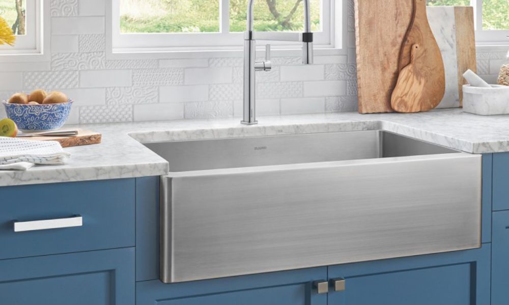 A stainless steel kitchen sink set against blue cabinets, showcasing a modern and stylish design.