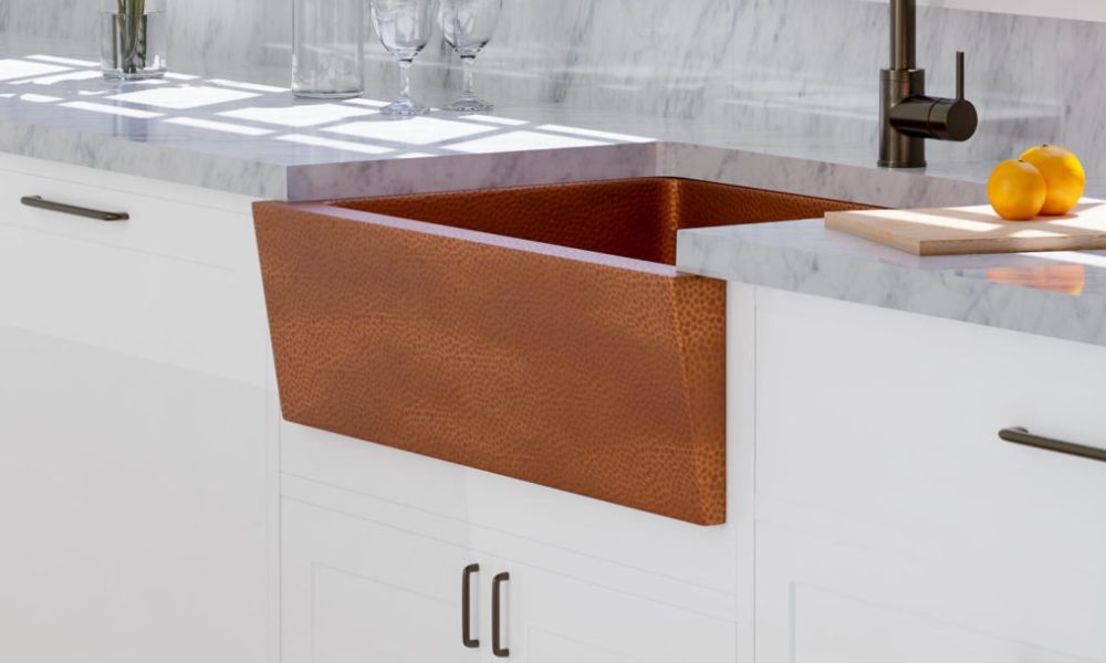 A copper sink installed in a kitchen featuring white cabinets, showcasing a modern and elegant design.