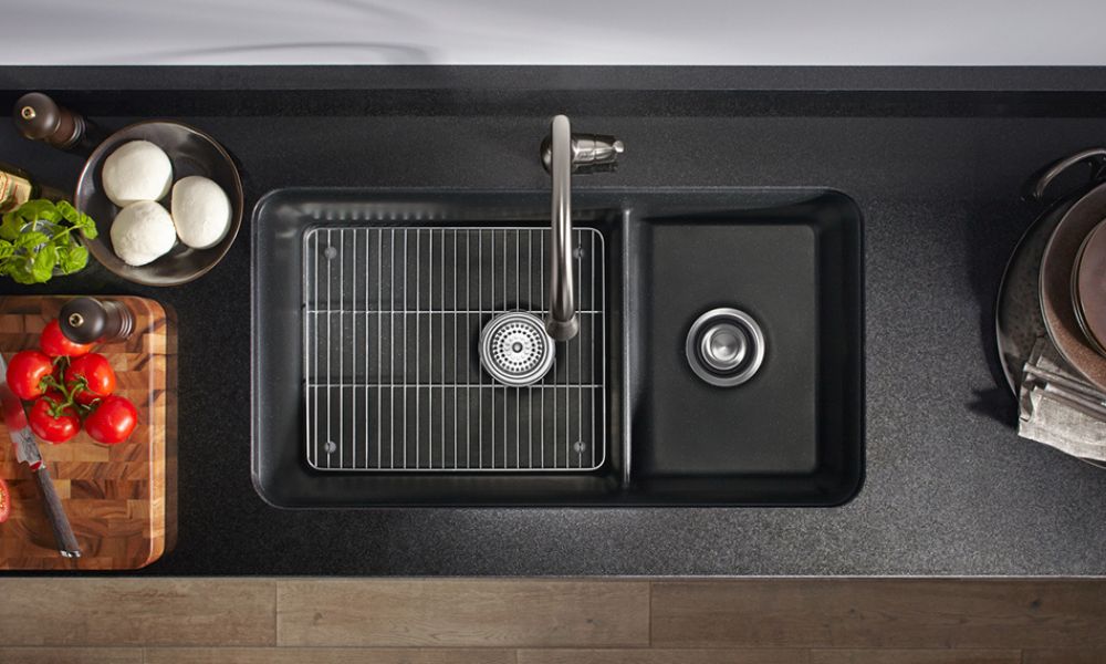 A modern kitchen sink with a black countertop and a sleek black sink, showcasing a minimalist design.