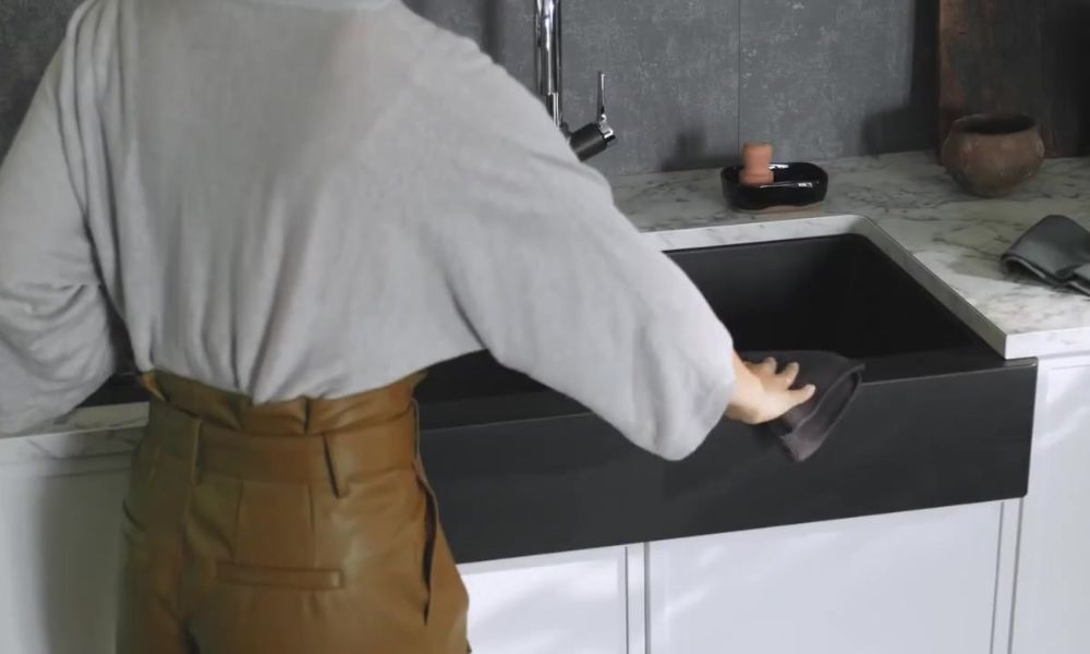 A woman is washing her hands at a kitchen sink, emphasizing hygiene in a domestic setting.