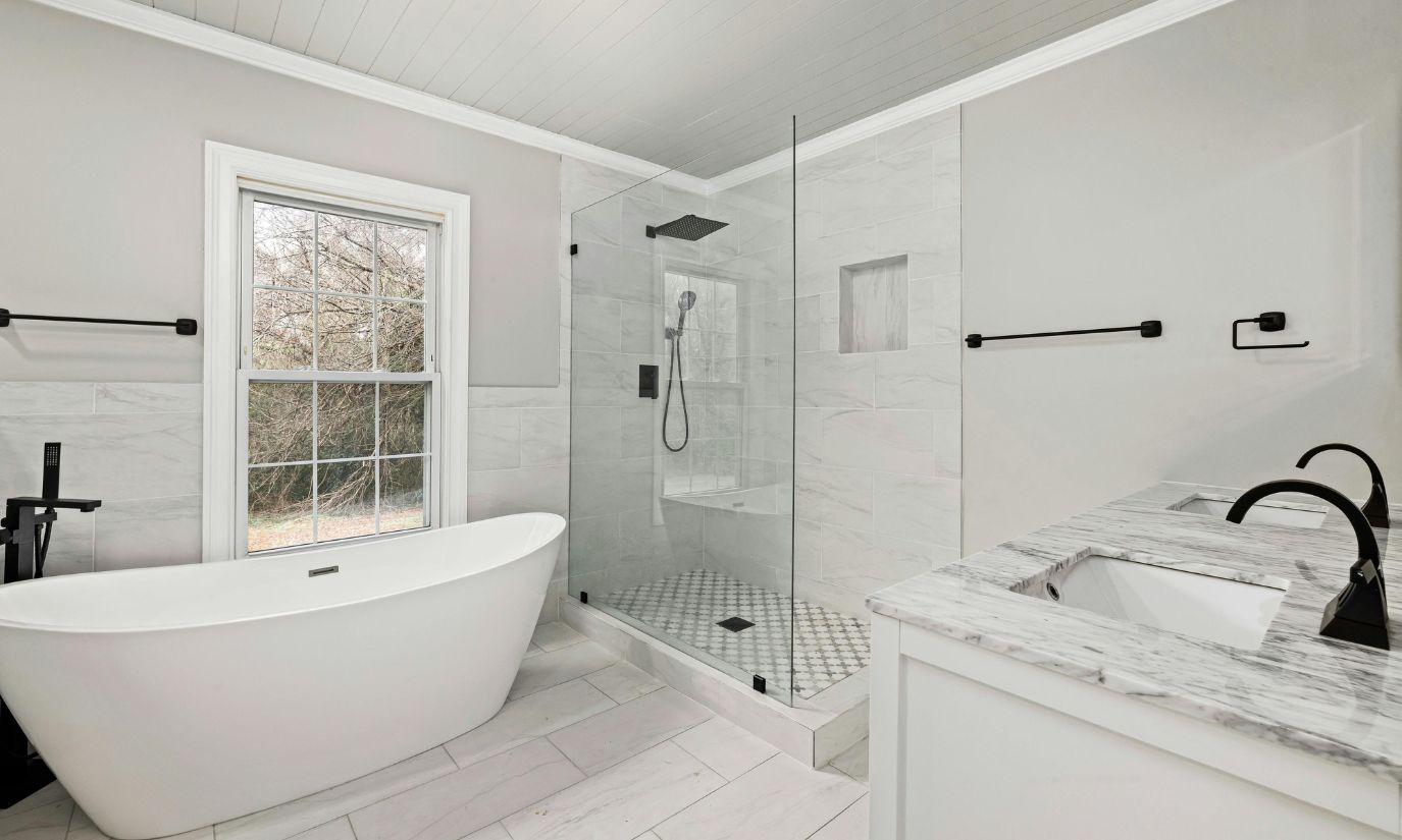 A spacious white bathroom featuring a large bathtub and a separate shower area