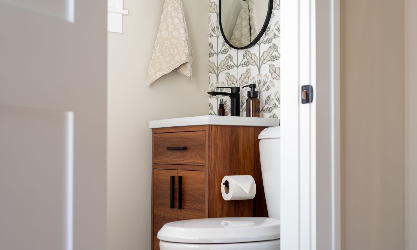 A bathroom featuring a toilet, sink, and mirror, showcasing a clean and organized space