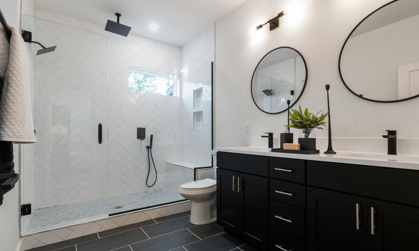 A modern bathroom featuring sleek black cabinets and elegant white tile flooring