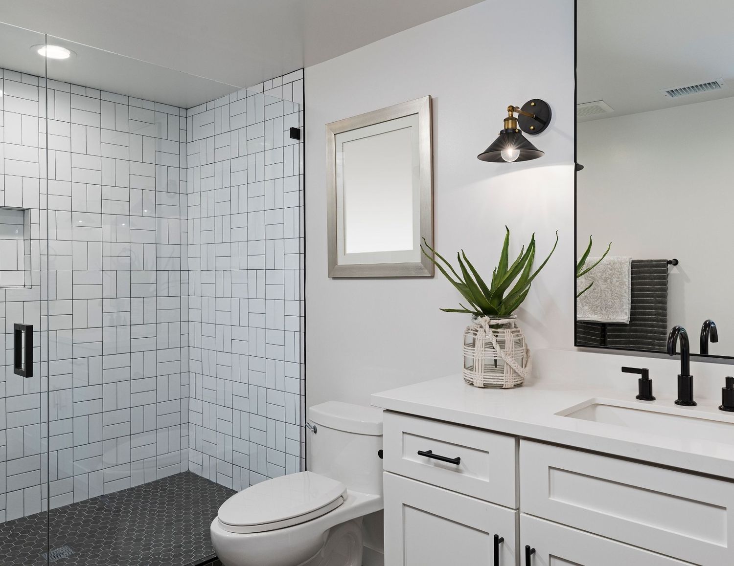 A modern bathroom featuring white tiles with black and white accents, showcasing a clean and stylish design.