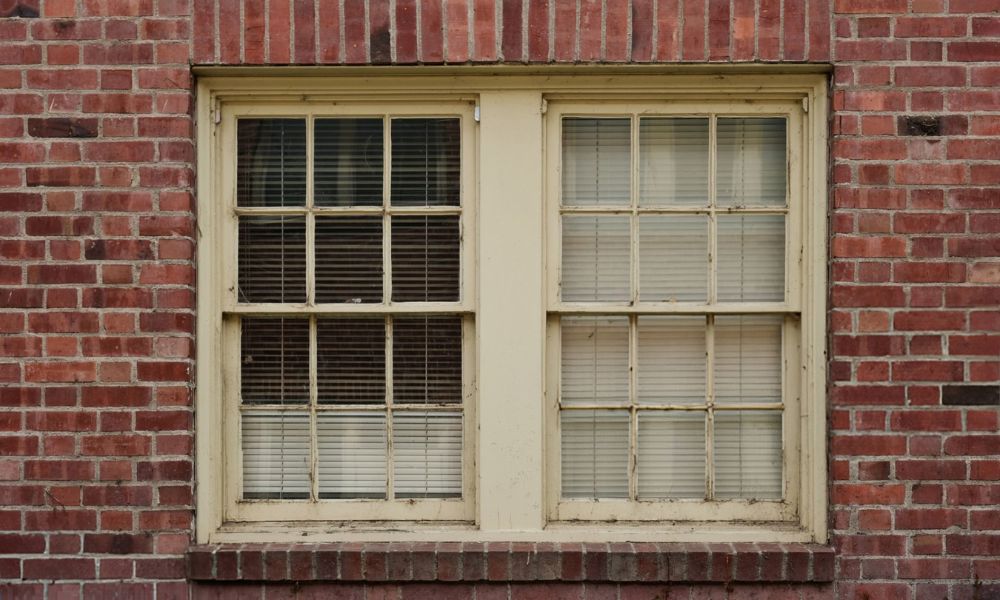 A white-framed window set into a textured brick wall, showcasing a blend of modern and traditional architectural elements.