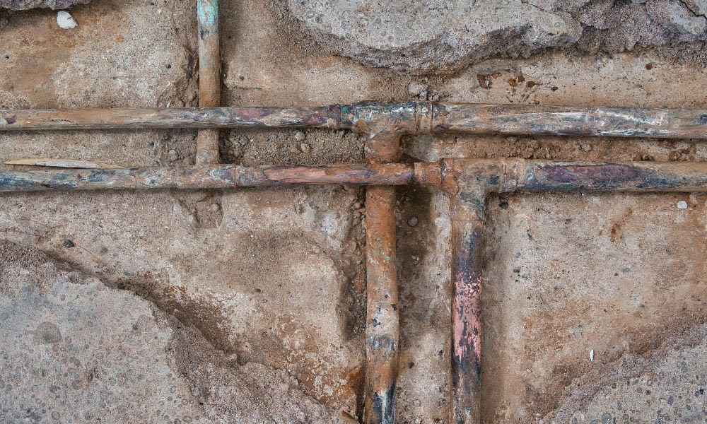 Close-up of a rusty pipe featuring a cross symbol, highlighting corrosion and wear on the metal surface.